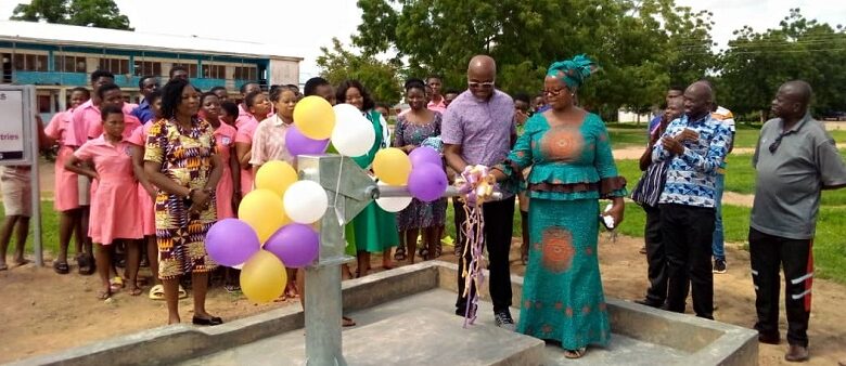 Navasco-borehole-Ms-Babachuwey-assisting-a-representative-from-the-Ministries-to-cut-a-ribbon-to-officially-inaugurate-the-borehole-looking-on-are-students-and-staff-of-the-school-780x338